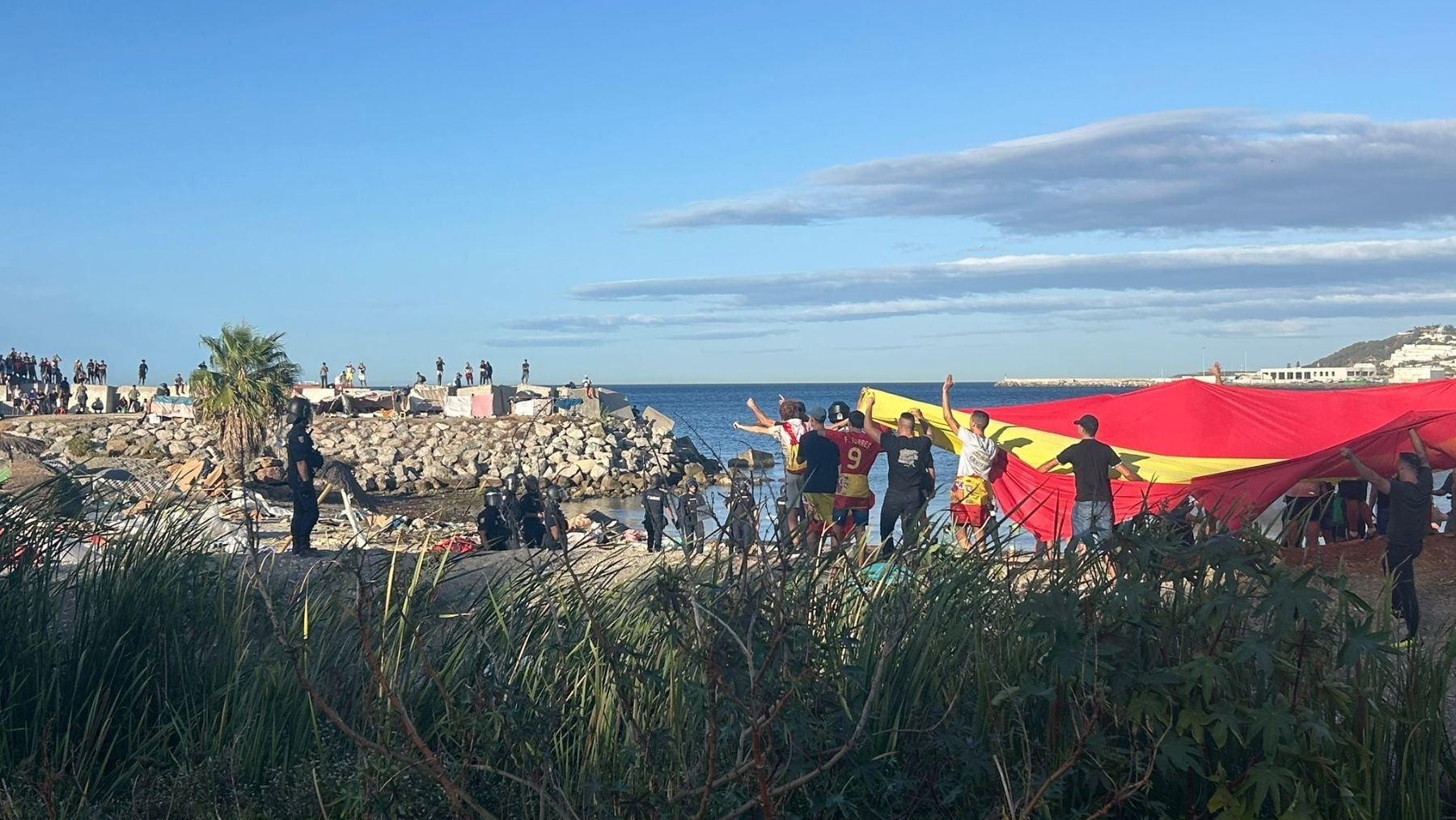 Vecinos de Ceuta rompen el cordón policial y queman las chabolas de los inmigrantes ilegales en la playa del Trampolín